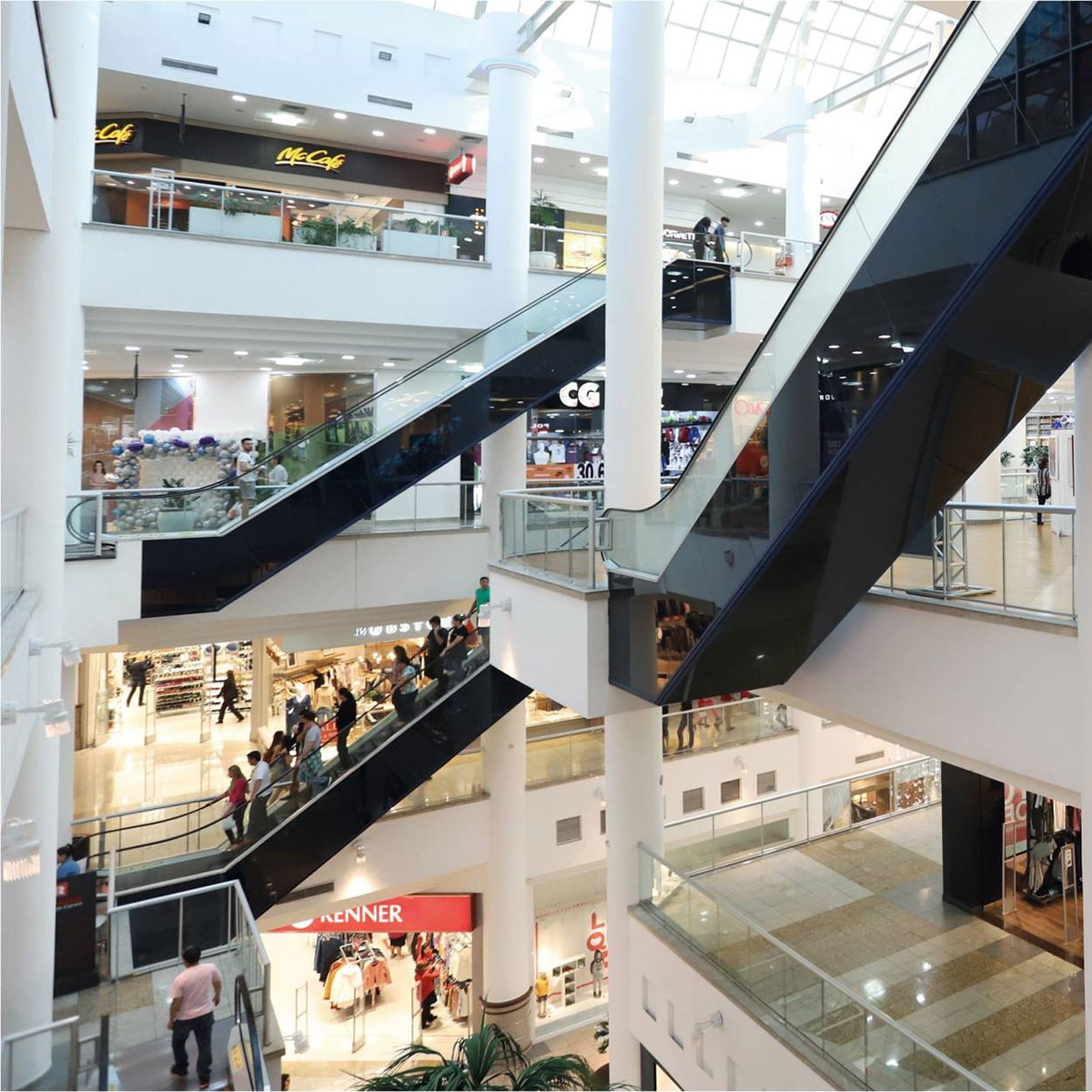 Movimento de pessoas circulando entre lojas e serviços em um centro comercial de Maringá.